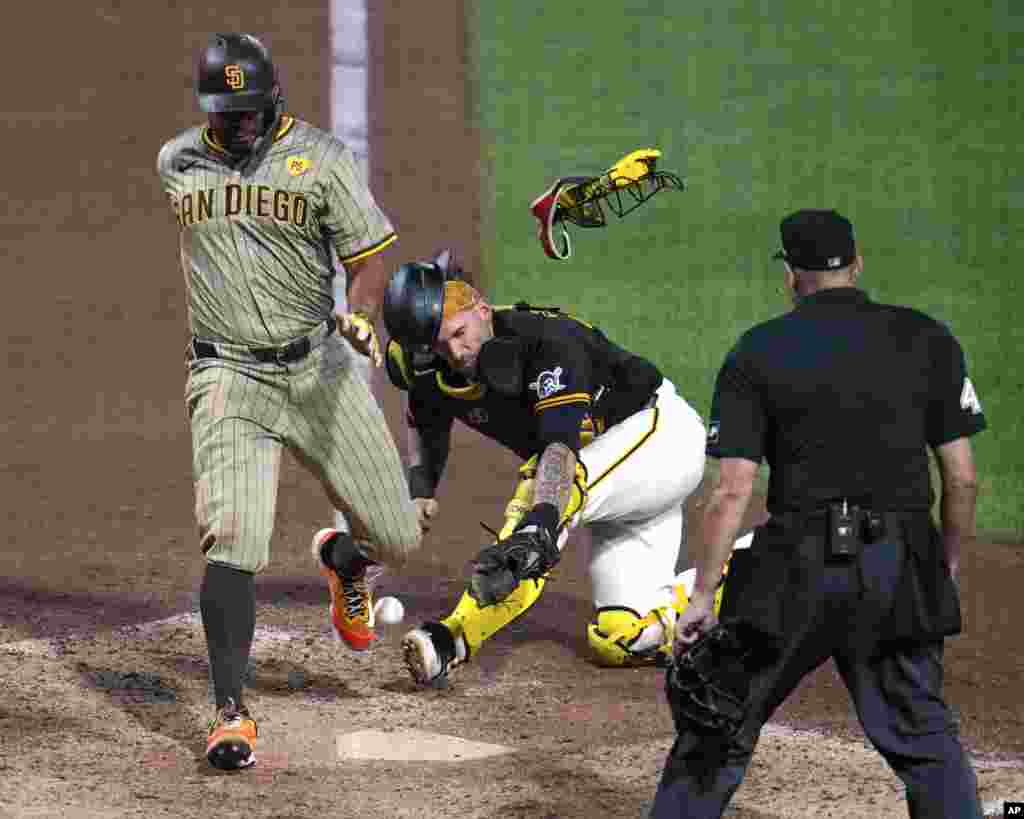 San Diego Padres&#39; Xander Bogaerts, left, knocks the ball out of the glove of Pittsburgh Pirates catcher Yasmani Grandal, center, to score from third on a sacrifice fly by Jackson Merrill off relief pitcher Colin Holderman during the tenth inning of a baseball game in Pittsburgh, Pennsylvania, Aug. 7, 2024.