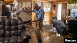 Bobby Smith, 70, the property manager of the River Ranch RV Park empties flood water out of their club house guitar after the property was damaged due to a flash flood in the aftermath of the Central New Mexico fires in Ruidoso Downs, New Mexico.