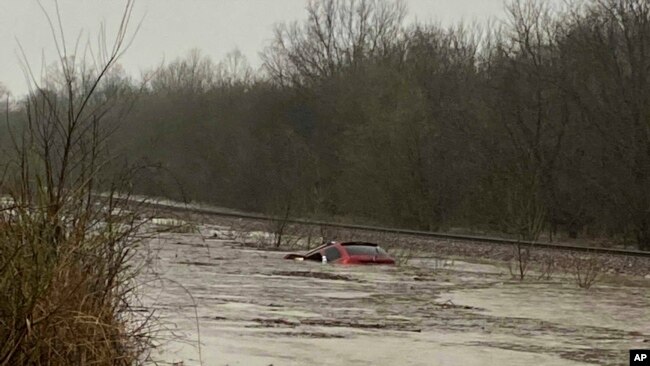 In this photo provided by Layton Hoyer, a red SUV is seen submerged in floodwater on Old Ritchey Road in Granby, Mo. March 24, 2023. Hoyer rescued an elderly woman from the car. (Layton Hoyer via AP)