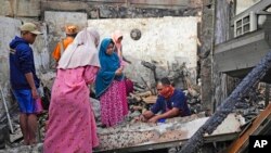 La gente inspecciona las ruinas de su casa en un vecindario afectado por un incendio en un depósito de combustible en Yakarta, Indonesia, el 4 de marzo de 2023.