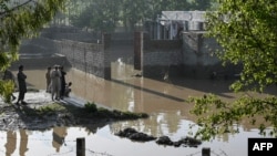 Residents stand near flood waters outside their homes following heavy rains in Pakistan's Khyber Pakhtunkhwa province, April 17, 2024. The province has now issued a flood alert due to glacial melting, officials said.