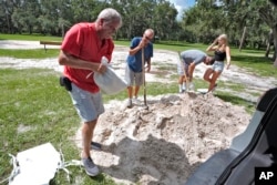 Roger Heim, left, and Terry Smith, second from left, both of Valrico, Florida, fill sand bags in preparation for a weekend storm at the Edward Medard Conservation Park in Plant City, Florida, Aug. 2, 2024.