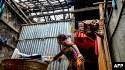 টেকনাফে ঘূর্ণিঝড় মোখা আঘাত হানার একদিন পর এক রোহিঙ্গা শরণার্থী নয়াপাড়া শরণার্থী শিবিরের একটি বাড়িতে তার রেখে যাওয়া জিনিসপত্র সংগ্রহ করছেন। ১৫ মে, ২০২৩।(ছবি মুনির উজ জামান/এএফপি)