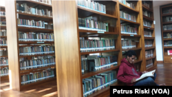 Seorang mahasiswa membaca buku di perpustakaan. (Foto: VOA/Petrus Riski)