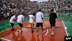 This photo taken July 30, 2023, shows workers wiping down the court following rain during halftime of a semifinal game of the grassroots basketball competition CunBA in Taipan village, Taijiang county, in southwestern China's Guizhou province.