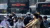 Para komuter tampak menggunakan masker ketika melewati distrik bisnis di Beijing, pada 26 Mei 2023. (Foto: AP/Mark Schiefelbein)
