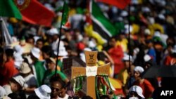 Pilgrims hold a cross-shaped sign as they wait for the start of the opening mass of the World Youth Day (WYD) gathering of young Catholics in Eduardo VII Park in Lisbon on Aug. 1, 2023. 