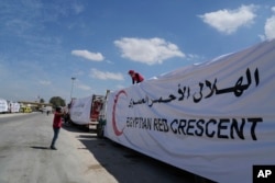 Egyptian drivers cover their trucks of humanitarian aids as they wait to cross the Rafah border crossing between Egypt and the Gaza Strip, March 23, 2024.