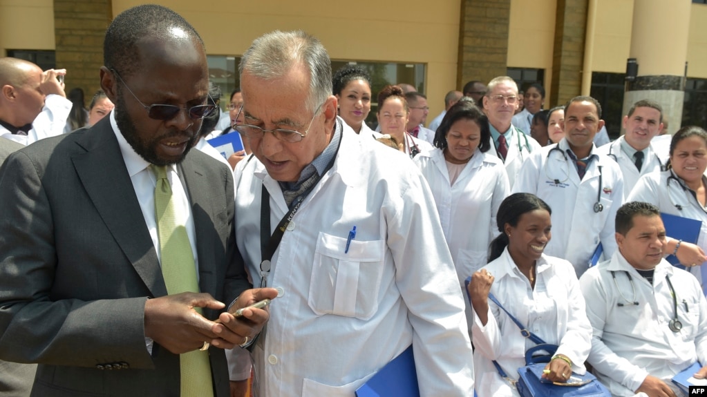 资料照片：肯尼亚基苏木省省长安扬·尼永戈教授（左）与参加位于内罗毕肯尼亚政府学院项目的100名古巴医生之一交谈。（2018年6月11日）(photo:VOA)