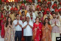 Mukesh Ambani, third left, poses with his family members and underprivileged couples during a mass wedding organized by him as part of pre-wedding celebrations of his youngest son, Anant Ambani, in Mumbai, India, July 2, 2024. (AP Photo/Rafiq Maqbool, File)