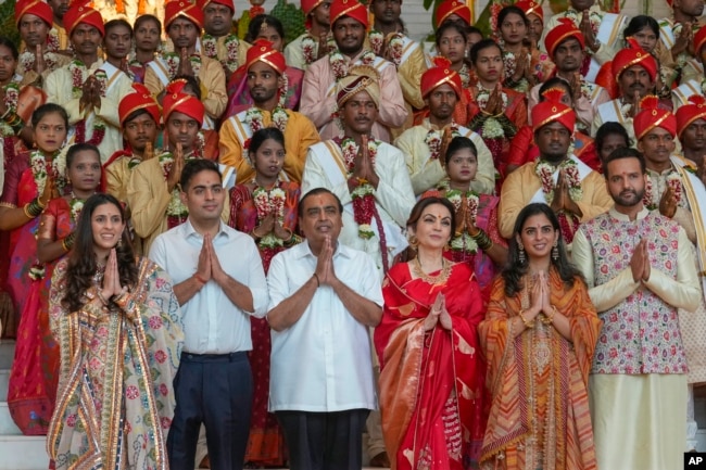 Mukesh Ambani, third left, poses with his family members and underprivileged couples during a mass wedding organized by him as part of pre-wedding celebrations of his youngest son, Anant Ambani, in Mumbai, India, July 2, 2024. (AP Photo/Rafiq Maqbool, File)