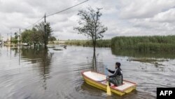 ARCHIVES - Un homme pagaie dans un bateau à Lenasia, en Afrique du Sud, le 10 décembre 2022, après de fortes pluies.