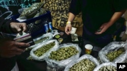 FILE - A vendor makes change for a marijuana customer at a cannabis marketplace in Los Angeles, April 15, 2019.