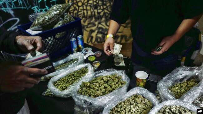 FILE - A vendor makes change for a marijuana customer at a cannabis marketplace in Los Angeles, April 15, 2019.