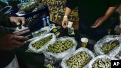 FILE - A vendor makes change for a marijuana customer at a cannabis marketplace in Los Angeles, April 15, 2019. 