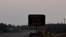 At upper left, a helicopter carrying a water bucket passes a sign warning of  smoke as wildfires threatened the Northwest Territories town of Yellowknife, Canada, Aug. 17, 2023.