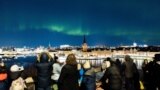 People watch the northern lights, aurora borealis, in central Stockholm, Sweden, Feb. 27, 2023.