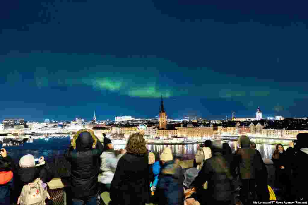 People watch the northern lights, aurora borealis, in central Stockholm, Sweden, Feb. 27, 2023.