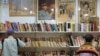 FILE - Visitors look at books at a booth displaying Chinese Communist Party posters at the 33rd Hong Kong Book Fair in the Wan Chai area of Hong Kong on July 19, 2023. 