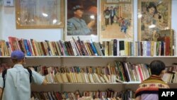 FILE - Visitors look at books at a booth displaying Chinese Communist Party posters at the 33rd Hong Kong Book Fair in the Wan Chai area of Hong Kong on July 19, 2023. 