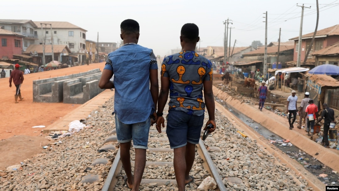FILE - Chris Agiriga (23), salah satu pria Nigeria yang ditangkap atas tuduhan menunjukkan kemesraan di depan umum dengan sesama jenis, berjalan dengan seorang temannya di jalan Mushin di Lagos, Nigeria, 14 Februari 2020. (REUTERS/Temilade Adelaja)
