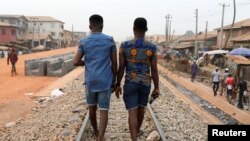 FILE - Chris Agiriga (23), salah satu pria Nigeria yang ditangkap atas tuduhan menunjukkan kemesraan di depan umum dengan sesama jenis, berjalan dengan seorang temannya di jalan Mushin di Lagos, Nigeria, 14 Februari 2020. (REUTERS/Temilade Adelaja)