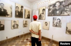 FILE - A Cambodian man examines photographs of Cambodians executed by the Khmer Rouge during their brutal reign of terror, 1975-1979, at the Toul Sleng Genocide Museum in Phnom Penh on June 15, 1997.