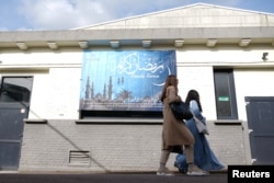 High school student Noha Fouad and her friend walks toward a classroom and in front of a banner that says "Ramadan Kareem" in the courtyard of the Averroes school, Lille, France, March 19, 2024.