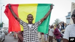 FILE - A man holds a national flag in the streets of Bamako, Mali, on Aug. 18, 2020. The Islamic State claimed that it killed 16 Malian soldiers the week of Aug. 3, 2023.