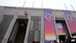 A protestor from Greenpeace hangs on the building with a banner during arrivals for a Nuclear Energy Summit at the Expo in Brussels, March 21, 2024.