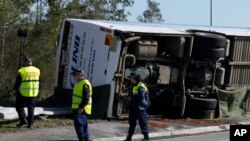 Polisi memeriksa sebuah bus yang terguling akibat kecelakaan di dekat kota Greta, Hunter Valley, utara Sydney, Australia, Senin, 12 Juni 2023. (AP/Mark Baker)