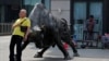 资料照：一名男子靠在北京一家证券交易所前的公牛铜像上。（2021年5月19日）