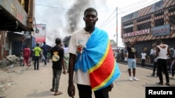 An anti-government demonstrator wears a Democratic Republic of Congo flag as he takes part in a riot in Kinshasa, Democratic Republic of Congo, May 20, 2023.