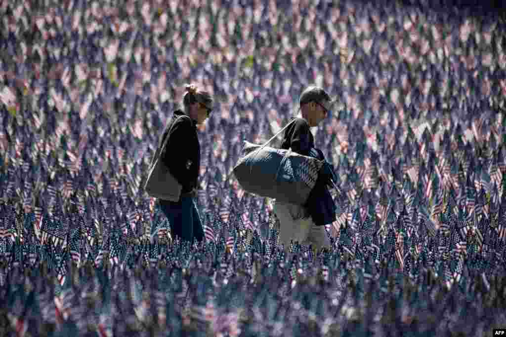 People tour a memorial with U.S. flags set next to the Soldiers and Sailors Monument by the Massachusetts Military Heroes Fund for Memorial Day, in Boston, Massachusetts.