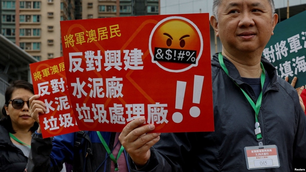 2023年3月26日，在中国香港，抗议者被要求在脖子上系上编号的挂牌，抗议一项填海造地和垃圾转运站项目，这是自颁布全面的国家安全法以来首次获得正式批准的示威活动之一。(photo:VOA)
