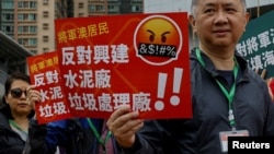 2023年3月26日，在中國香港，抗議者被要求在脖子上繫上編號的掛牌，抗議一項填海造地和垃圾轉運站項目，這是自頒佈全面的國家安全法以來首次獲得正式批准的示威活動之一。