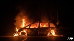 A car is on fire on Riviere Salee&#39;s main road in Noumea, in the French Pacific territory of New Caledonia. A fresh surge of unrest hit the territory, with several buildings set on fire overnight, including a police station and a town hall, authorities said.