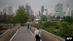 Seorang perempuan berjalan-jalan di sepanjang jalan layang di taman Benjakitti, Bangkok, 19 Januari 2024. (MANAN VATSYAYANA / AFP)