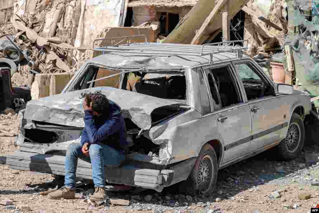 A youth sits on a damaged vehicle outside a destroyed building in the aftermath of an overnight Israeli airstrike on the city of Baalbek in east central Lebanon. (Photo by AFP)