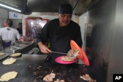 Chef Arturo Rivera Martínez prepares an order of tacos at the Tacos El Califa de León taco stand, in Mexico City, on May 15, 2024. Tacos El Califa de León is the first ever taco stand to receive a Michelin star from the French dining guide. (AP Photo/Fernando Llano)