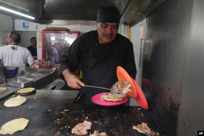 Chef Arturo Rivera Martínez prepares an order of tacos at the Tacos El Califa de León taco stand, in Mexico City, on May 15, 2024. Tacos El Califa de León is the first ever taco stand to receive a Michelin star from the French dining guide. (AP Photo/Fernando Llano)