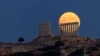 The moon rises behind the ancient marble temple of Poseidon at Cape Sounion, about 70 Km (45 miles) south of Athens, Greece, July 20, 2024.