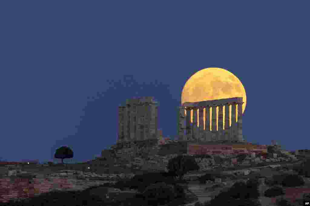 The moon rises behind the ancient marble temple of Poseidon at Cape Sounion, about 70 Km (45 miles) south of Athens, Greece, July 20, 2024. 