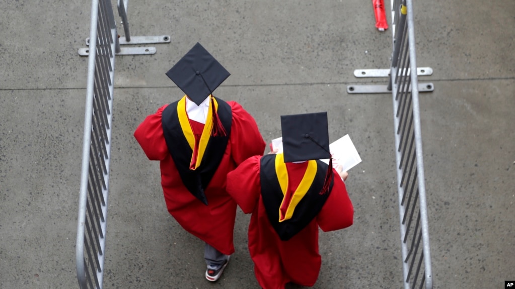 FILE - In this May 13, 2018, file photo, new graduates walk at the start of the Rutgers University graduation ceremony in New Jersey. Americans are saying the U.S. higher education system is headed in the “wrong direction.” (AP Photo/Seth Wenig, File)