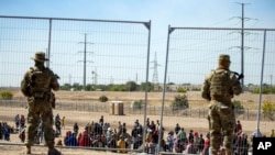 Мигранты стоят в очереди у пограничного забора, который охраняют военнослужащие Национальной гвардии Техаса. Эль-Пасо, штат Техас. 10 мая 2023 года.