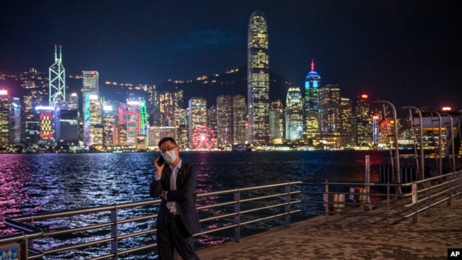 FILE - A man talks on his phone against the backdrop of the skyline in Hong Kong, Oct. 19, 2022.