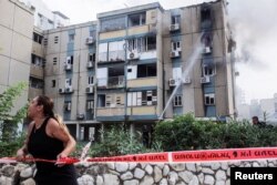 A woman calls out as smoke rises from a residential apartment building hit by a rocket fired from the Gaza Strip, in Tel Aviv, Israel, Oct. 27, 2023.