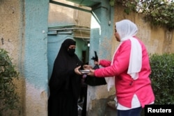 A volunteer distributes meals and food supplies to families, in Helwan, a suburb of Cairo, Egypt, Feb. 10, 2023.