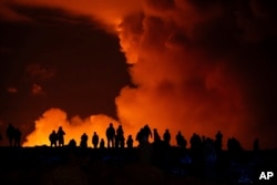 Spectators watch plumes of smoke from volcanic activity between Hagafell and Stori-Skogfell, Iceland, March 16, 2024.