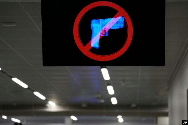 A television displays a "no guns" sign at the Transportation Security Administration security area at the Hartsfield-Jackson Atlanta International Airport on Wednesday, Jan. 25, 2023, in Atlanta. (AP Photo/Brynn Anderson)